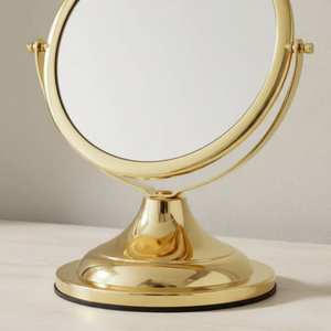 Espelho de aumento para maquiagem, redondo, detalhe da base de mesa Gold sobre superfície clara.