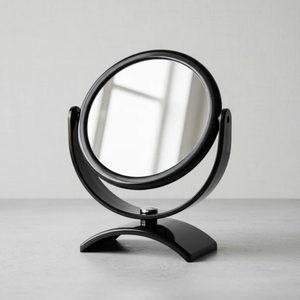 Espelho de aumento para maquiagem, redondo, de mesa, acabamento preto, em ambiente interno neutro, foco no espelho central e na base.