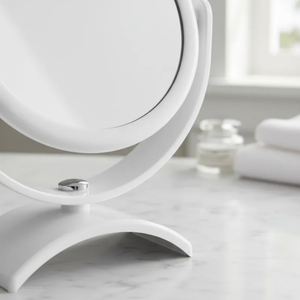 Espelho de aumento para maquiagem, redondo, de mesa, acabamento branco, sobre bancada de banheiro, foco na base e no aro.