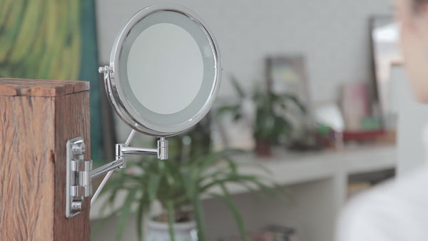 Espelho com LED para maquiagem MOBILE LUX instalado na parede e sendo utilizado por uma modelo